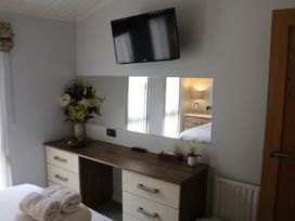 A bedroom with a dresser and television at High View Lodge near Troutbeck Bridge