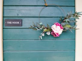 A door with a floral wreath and a sign reading THE NOOK at The Nook in Royal Wootton Bassett