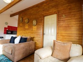 A living room with two sofas and decorative plates on a wooden wall at The Nook in Royal Wootton Bassett