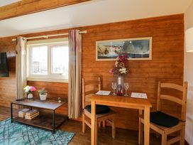 A wooden dining table with two chairs and a vase with flowers next to a coffee table with plants under a window at The Nook in Royal Wootton Bassett