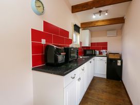 A kitchen with white cabinets black countertop red backsplash and appliances at The Nook in Royal Wootton Bassett