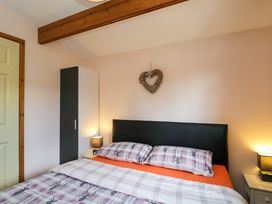 A bedroom with a bed with plaid deer pillows and duvet a black headboard a white and black wardrobe and two bedside tables with lamps at The Nook in Royal Wootton Bassett
