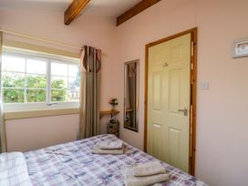A bedroom with a bed folded towels a window curtains a door a mirror and a small shelf with flowers at The Nook in Royal Wootton Bassett