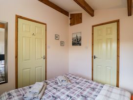 A bedroom with a bed covered in patterned bedding two closed doors a mirror and framed pictures on the wall at The Nook in Royal Wootton Bassett
