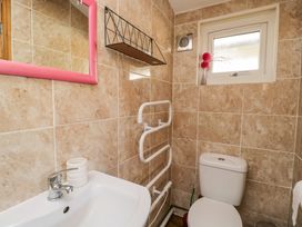 A bathroom with a toilet sink pink framed mirror window and wall mounted shelf at The Nook in Royal Wootton Bassett
