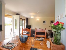A dining table set with glasses and plates next to a vase of flowers in a living room at Stone Water Cottage in Strathpeffer