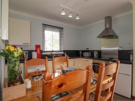 A kitchen with wooden dining table and chairs a stove and a refrigerator at Stone Water Cottage in Strathpeffer