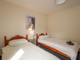 A bedroom with two single beds a bedside table with a lamp and a painting on the wall at Stone Water Cottage in Strathpeffer