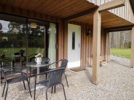 An outdoor seating area with a metal table and four black chairs next to a white door at Stone Water Cottage in Strathpeffer