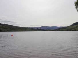 A lake surrounded by forested hills with a red buoy floating in the water at Stone Water Cottage in Strathpeffer