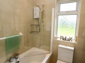 A bathroom featuring a bathtub with shower, toilet, and window at Rowantree, Beaufort, County Kerry