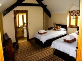 A bedroom with two beds and a bathroom at Tyn Y Celyn Canol Clocaenog near Ruthin