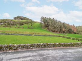 A view of a grassy hill with trees and a stone wall at Briws and 963354 together they sleep 35