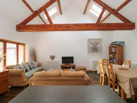A living room with a sofa and dining area at Riverside Barn in Gilwern near Crickhowell and Abergavenny