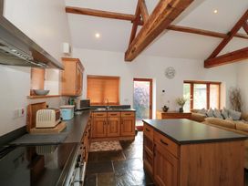 A kitchen with wooden cabinets and a dining area at Riverside Barn Gilwern near Crickhowell and Abergavenny