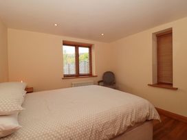 A bedroom with a bed and windows at Riverside Barn in Gilwern near Crickhowell and Abergavenny