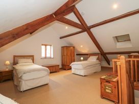 A bedroom with two beds and wooden furniture at Riverside Barn in Gilwern near Crickhowell and Abergavenny