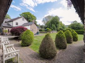 An outdoor garden area with hedges and chairs at Riverside Barn in Gilwern near Crickhowell and Abergavenny