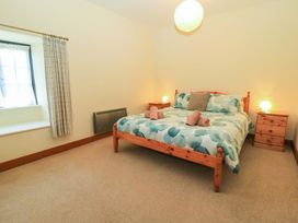 A bedroom with a wooden bed with patterned bedding and two bedside tables with lamps at Keepers Cottage in Winterborne Stickland