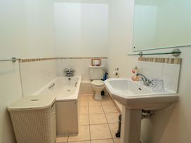A bathroom with a bathtub toilet sink and a laundry basket at Keepers Cottage in Winterborne Stickland