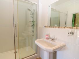 A bathroom with a shower cubicle and a white pedestal sink with a mirror above at Keepers Cottage in Winterborne Stickland