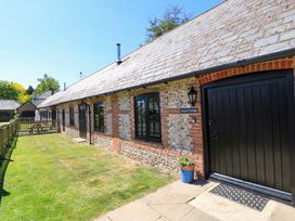 The exterior of a stone and brick cottage with black doors and windows and a grassy yard at Keepers Cottage Winterborne Stickland