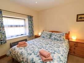 A bedroom with a double bed with patterned bedding two side tables with lamps a window with patterned curtains and folded towels on the bed at New Barn in Winterborne Stickland