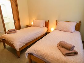 A bedroom with two single beds with wooden frames towels on beds and a door leading to a bathroom at New Barn in Winterborne Stickland