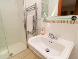 A bathroom with a white sink and silver faucet a towel hanging on a metal rack and a glass shower enclosure at New Barn in Winterborne Stickland