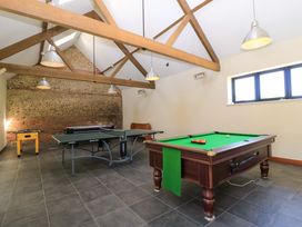 A game room with a pool table ping pong table foosball table and wooden beams on the ceiling at New Barn in Winterborne Stickland