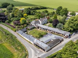 An aerial view of a house and barn surrounded by greenery at New Barn in Winterborne Stickland