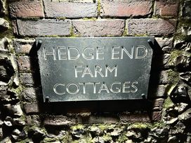 A sign for Hedge End Farm Cottages on a brick wall at Hedge End Farm Cottages Winterborne Stickland