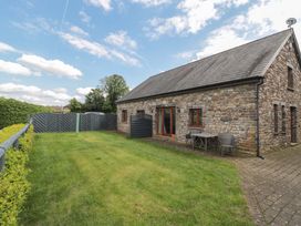 A garden with a stone house and a table with chairs at Longside in Gilwern