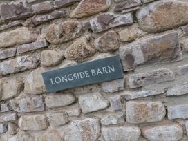 A stone wall with a plaque reading Longside Barn in Gilwern