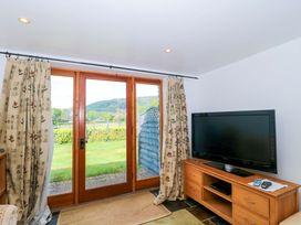 A living room with a TV and windows at Longside in Gilwern