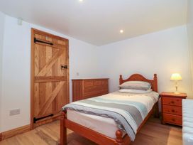 A bedroom with a bed, dresser and lamp at Longside in Gilwern