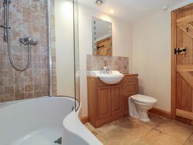 A bathroom with a shower, bath tub, sink, and toilet at Longside in Gilwern