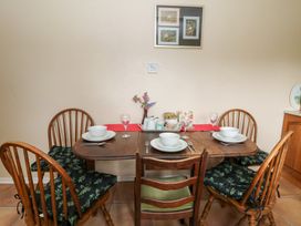 A dining table set with bowls, plates, glasses, cutlery, and a vase of flowers at Bryn yr Haf in Llanfair Clydogau near Lampeter