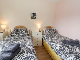 A bedroom with two single beds with patterned bedding towels and bedside tables with lamps at Bryn yr Haf in Llanfair Clydogau near Lampeter