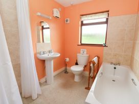 A bathroom with a bathtub toilet and sink with orange walls and tiled accents at Bryn yr Haf in Llanfair Clydogau near Lampeter