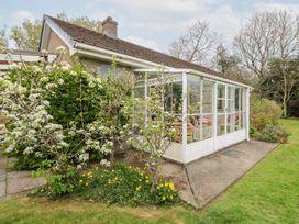 A glass conservatory attached to a house with blossoming trees and a lawn at Bryn yr Haf in Llanfair Clydogau near Lampeter