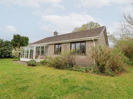A single-story house with a conservatory and garden bushes at Bryn yr Haf in Llanfair Clydogau near Lampeter