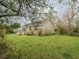 An exterior view of a single-story house with a glass conservatory and surrounding garden at Bryn yr Haf Llanfair Clydogau near Lampeter