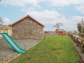 An outdoor area with a slide and buildings at Rhianwen, Plas Moelfre Hall Barns Llanrhaeadr-ym-Mochnant