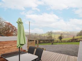 An outdoor area with a table and chairs and an umbrella at Rhianwen, Plas Moelfre Hall Barns