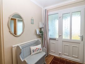 A hallway with a bench and mirror at Salty Puffin in Benllech