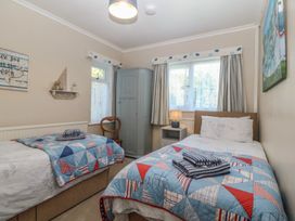 A bedroom with two beds and a wardrobe at Salty Puffin in Benllech