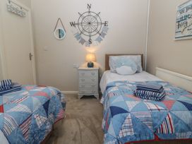 A bedroom with two single beds and a chest of drawers at Salty Puffin in Benllech