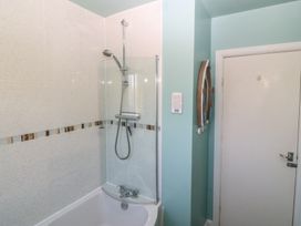 A shower over a bathtub in a bathroom at Salty Puffin Benllech
