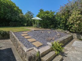 A garden with a stone patio and seating at Salty Puffin in Benllech